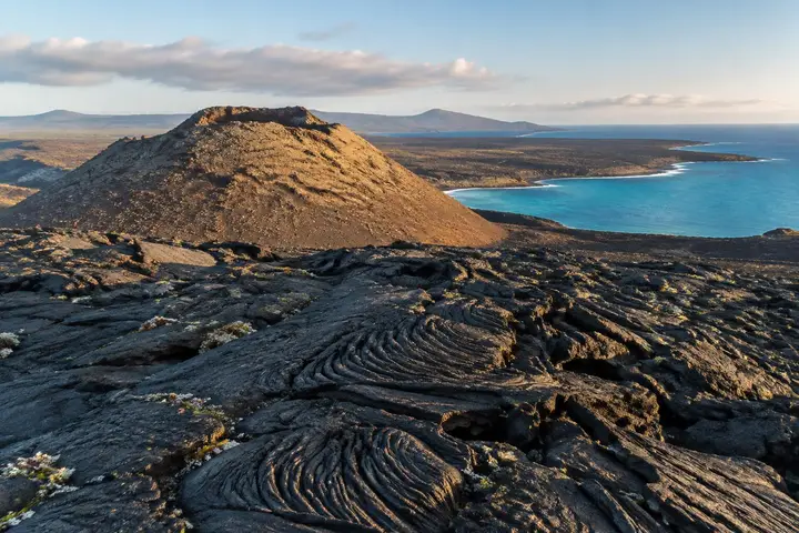 AI-generated illustration of young black lava flows and a tuff cone beside the turquoise Galápagos coastline
